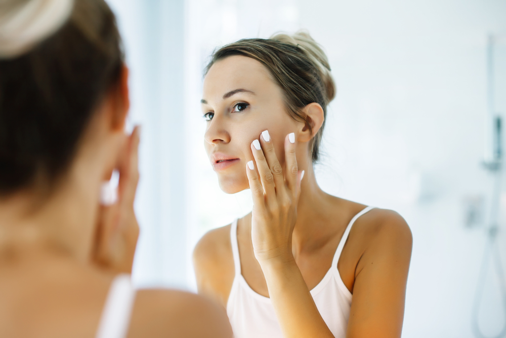 Woman examining her skin in the mirror after a skin treatment